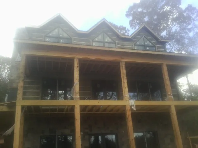 Dormers and porch framing on a large log home under construction — Roof Coating work by our crew in High Point